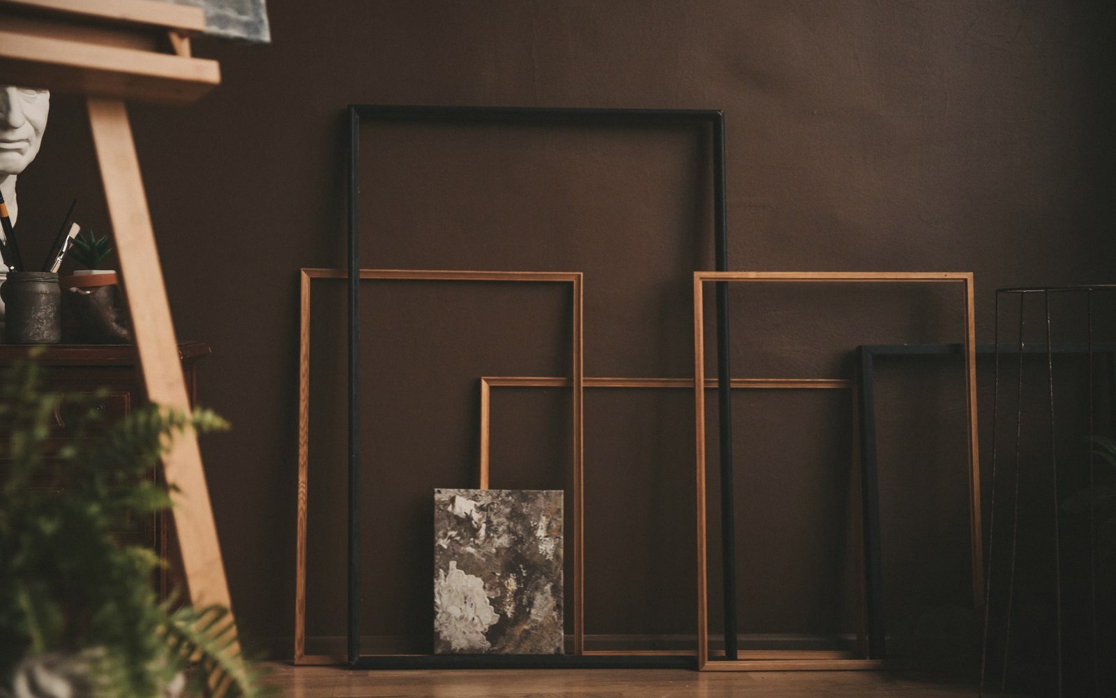 Empty wooden and black frames leaning against a wall in an art studio