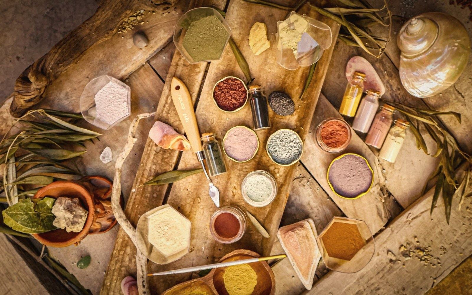 Raw earth pigment powder heaped on a glass grinding slab, close-up, warm studio light