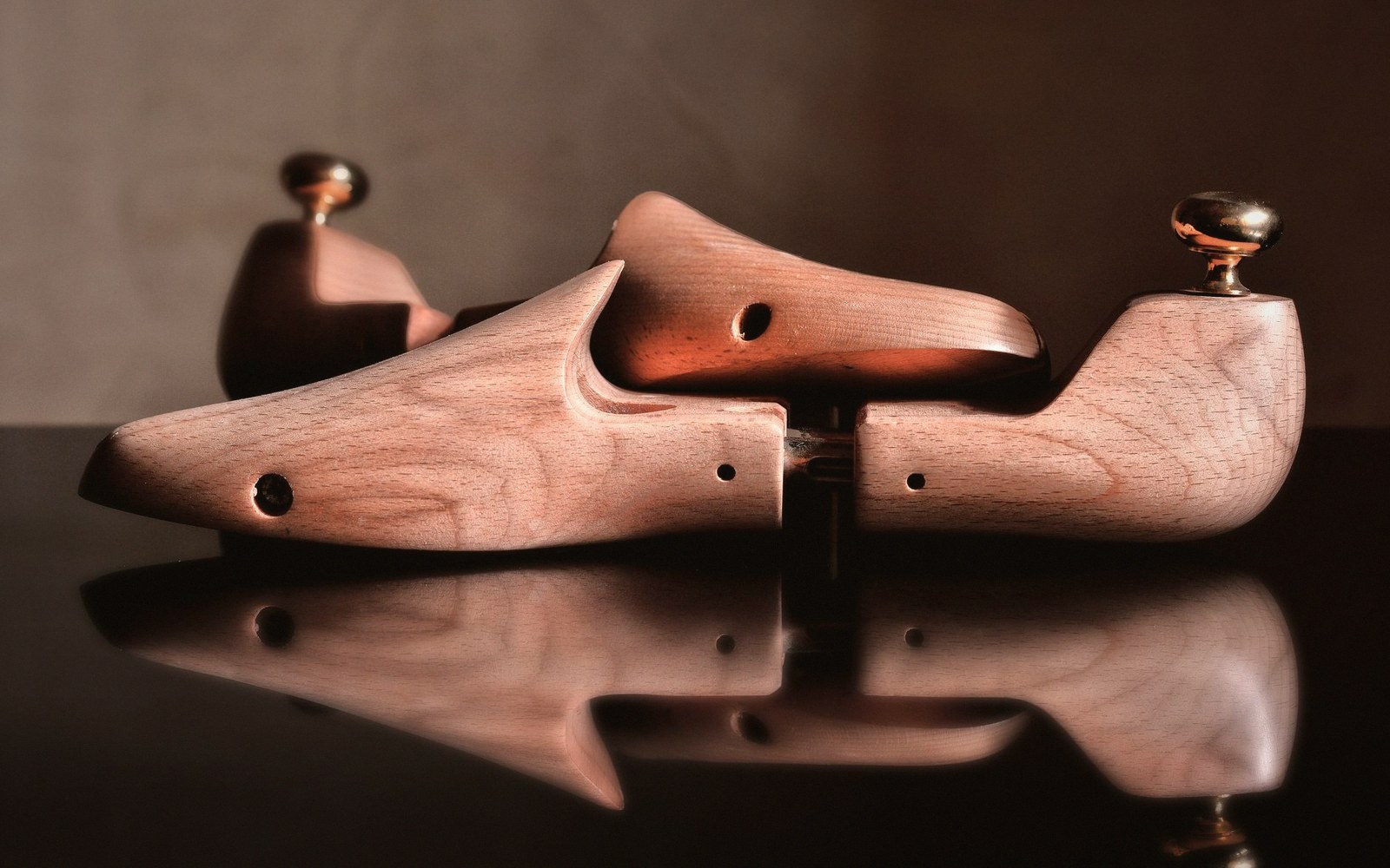 Corner of a wooden stretcher bar with expansion keys inserted, workbench surface below, overhead lamp